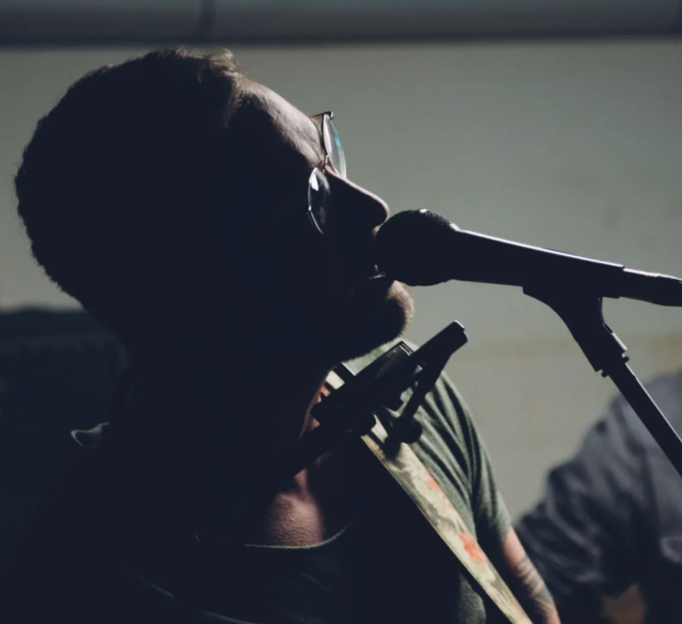 Bricky Waters singt am Mikrofon, Mundharmonika-Halter vor der Brust